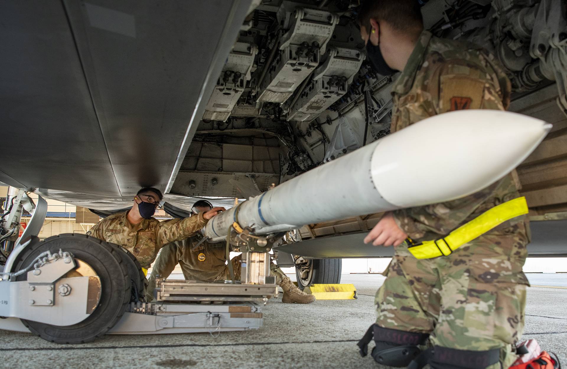 During the 325th Aircraft Maintenance Squadron's weapons load competition at Eglin Air Force Base in Florida on December 17th, a load crew guided an AIM-120 missile under their aircraft. Two weapons load crews competed to determine who could load an AIM-120 and a GBU-32 onto their F-22 Raptor the fastest and with the fewest errors. (U.S. Air Force photo/Samuel King Jr.)